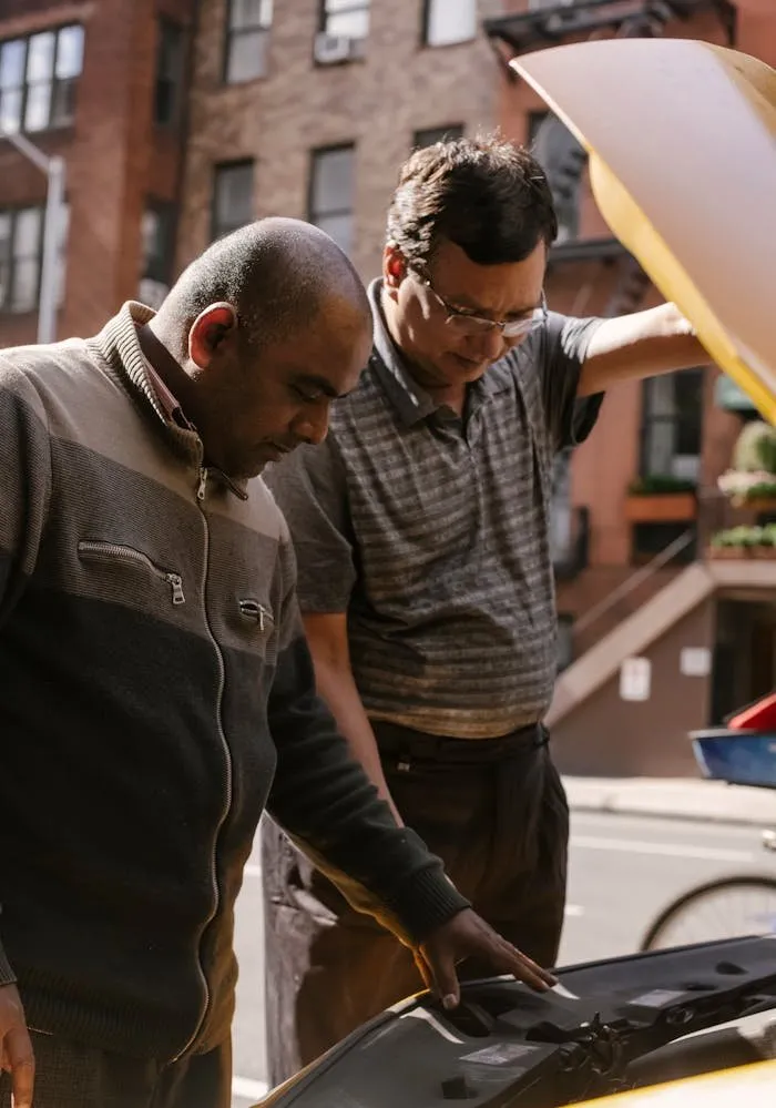 Two people looking under the hood of a car