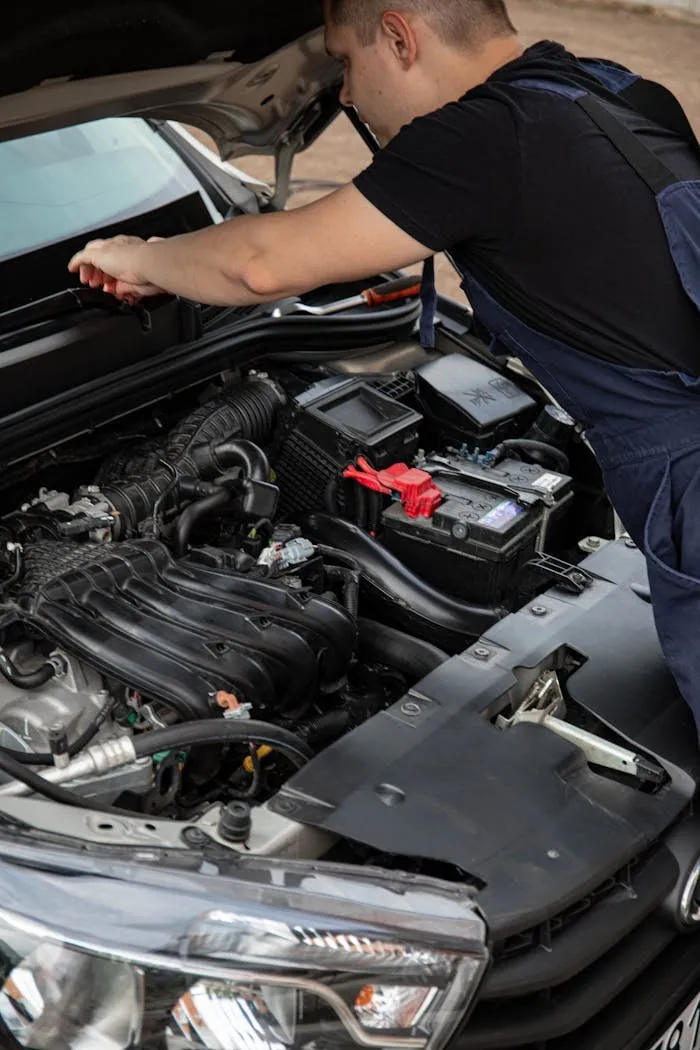 Mechanic working near a car battery under the hood