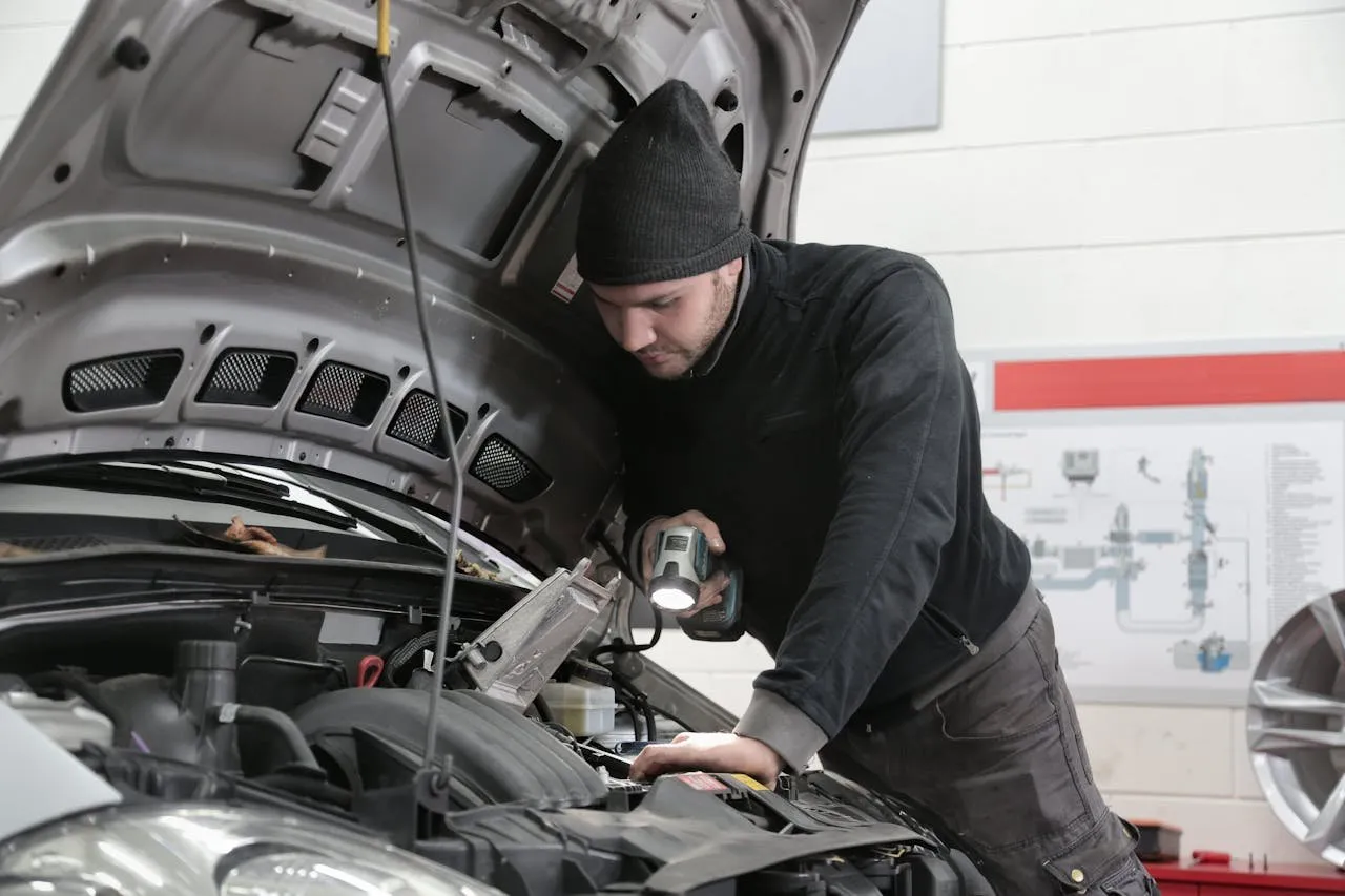 Mechanic inspecting a vehicle with a flashlight